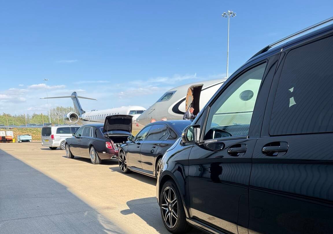 Luxury chauffeur vehicles waiting beside private jets at a London airport