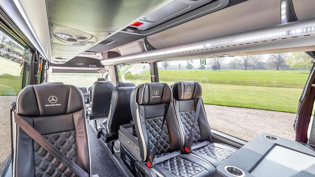 Spacious minibus interior with individual passenger seats and ceiling lights