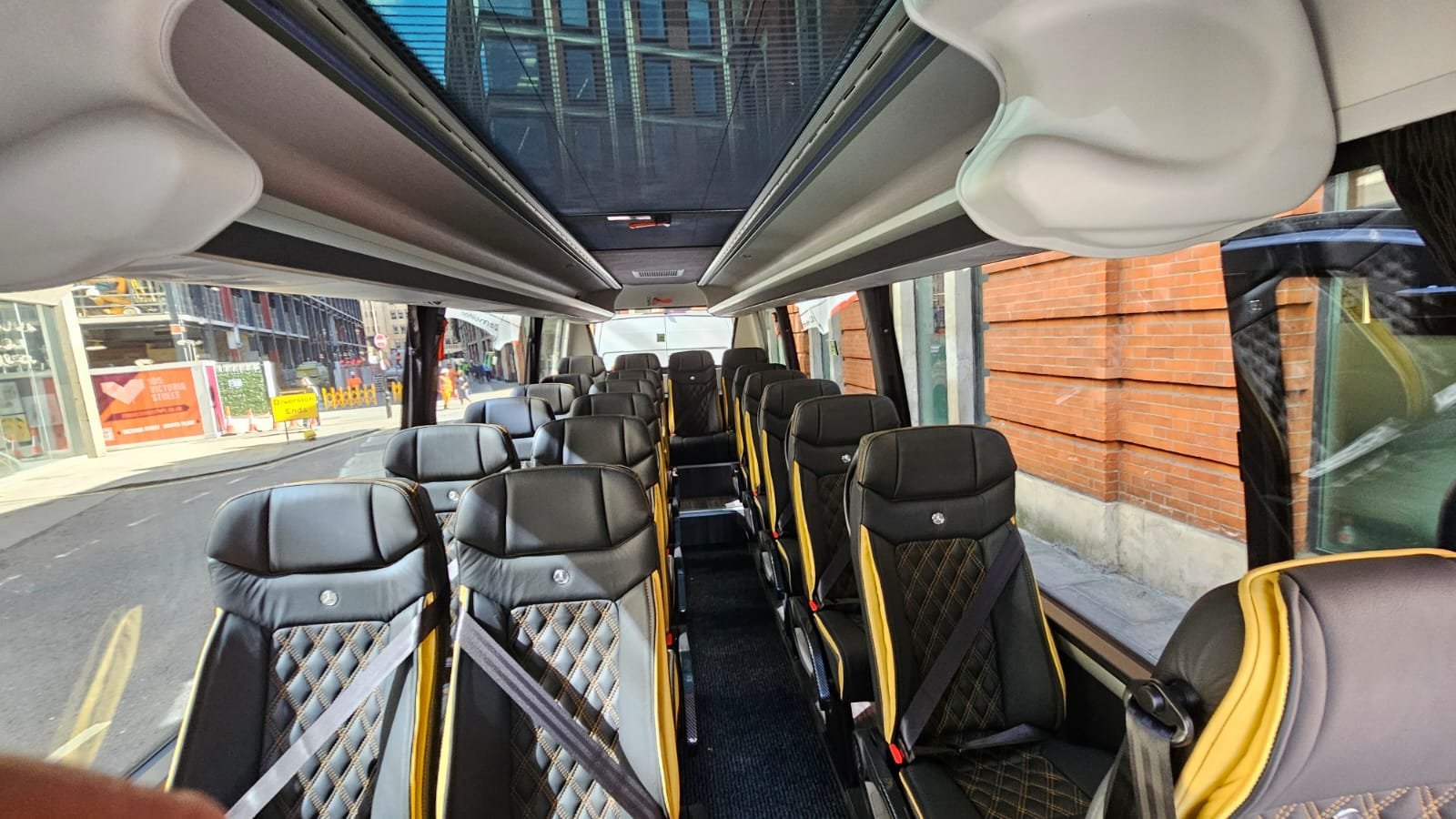 Executive minibus interior with individual leather seats and panoramic windows.